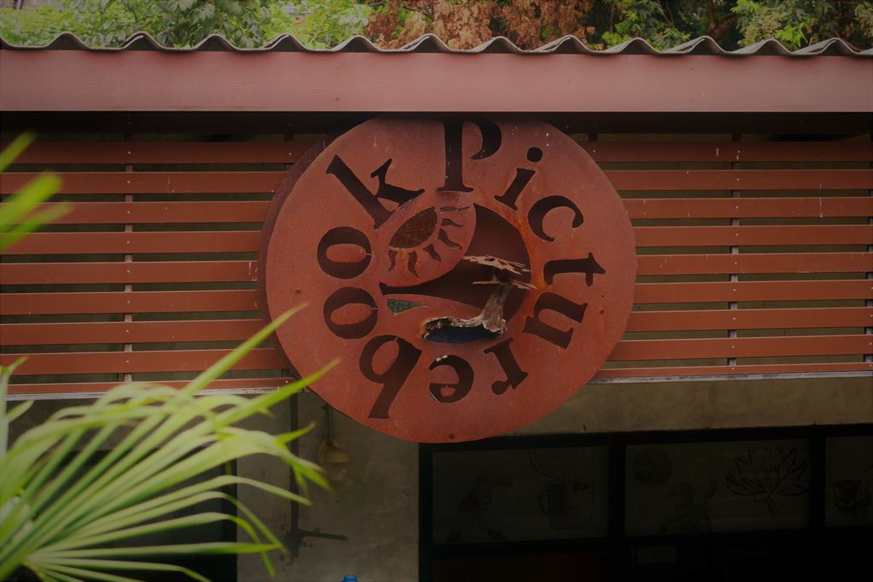 Una señal circular con el texto 'OK PICTUR' en la fachada de un edificio.