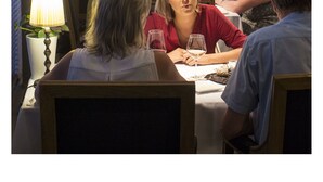A restaurant with tables set for dining, a waiter attending to guests, and a view of trees outside. - Hotel Restaurant Vous lé Vous (Hasselt)