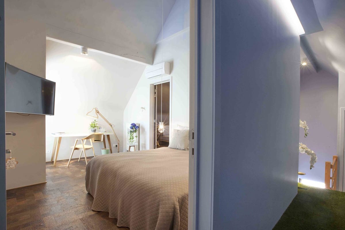 A bedroom with a bed, a desk, a chair, and a television.