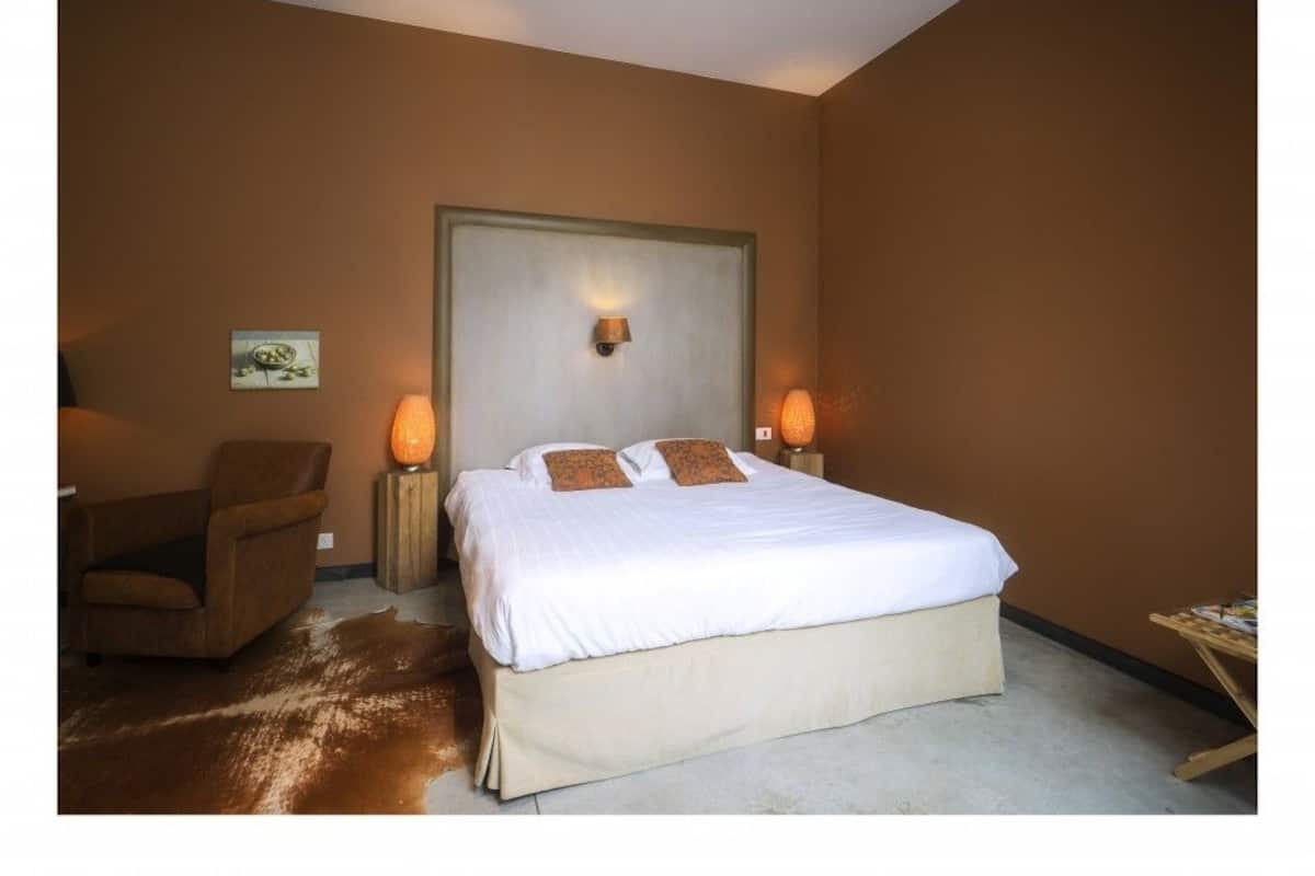 A bedroom with a large bed, two bedside lamps, a chair, and a small table.