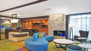 Una hall moderna con una reception, un divano blu, un caminetto e un'ampia finestra con tende.