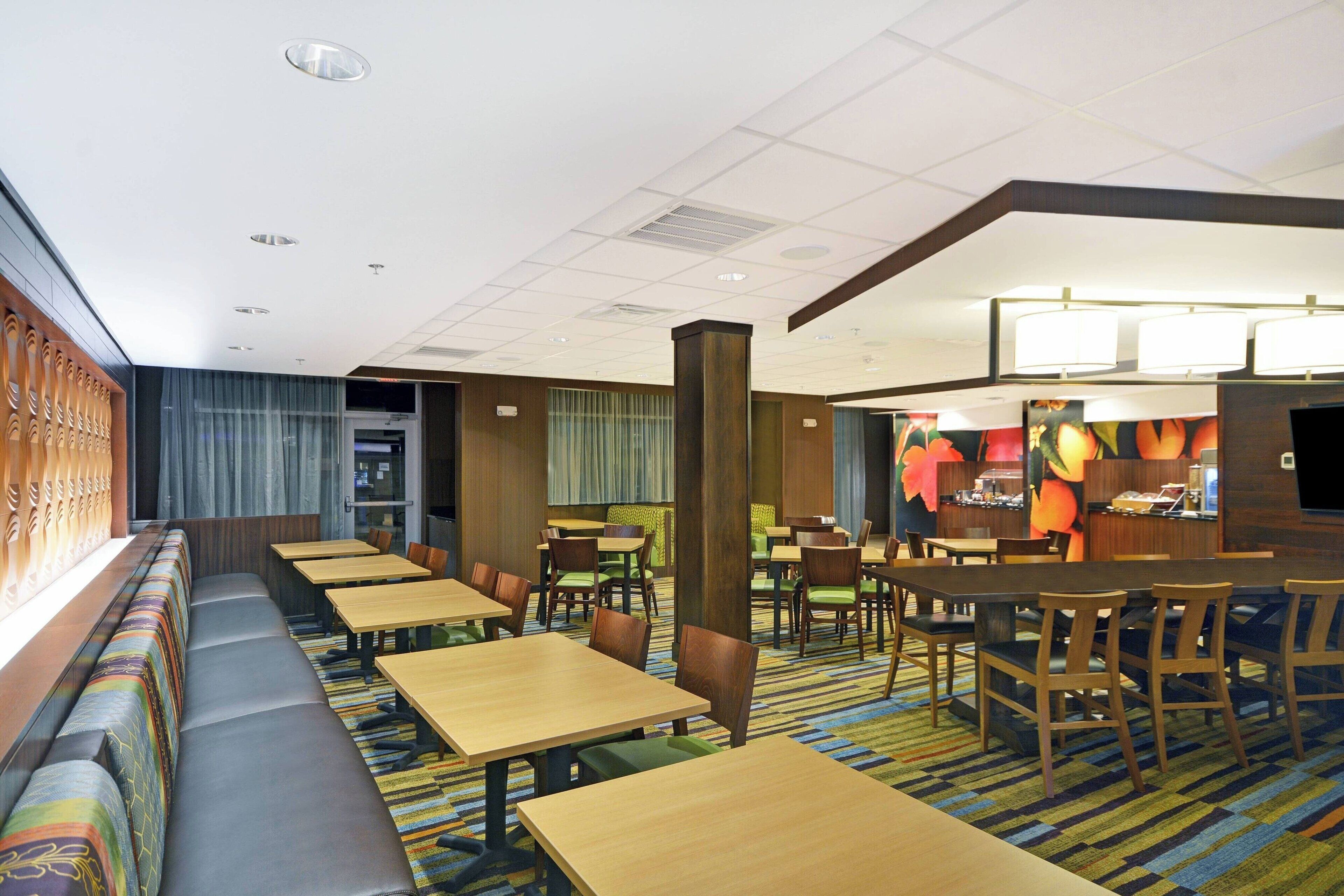 A hotel lobby with seating areas, tables, and a reception desk.
