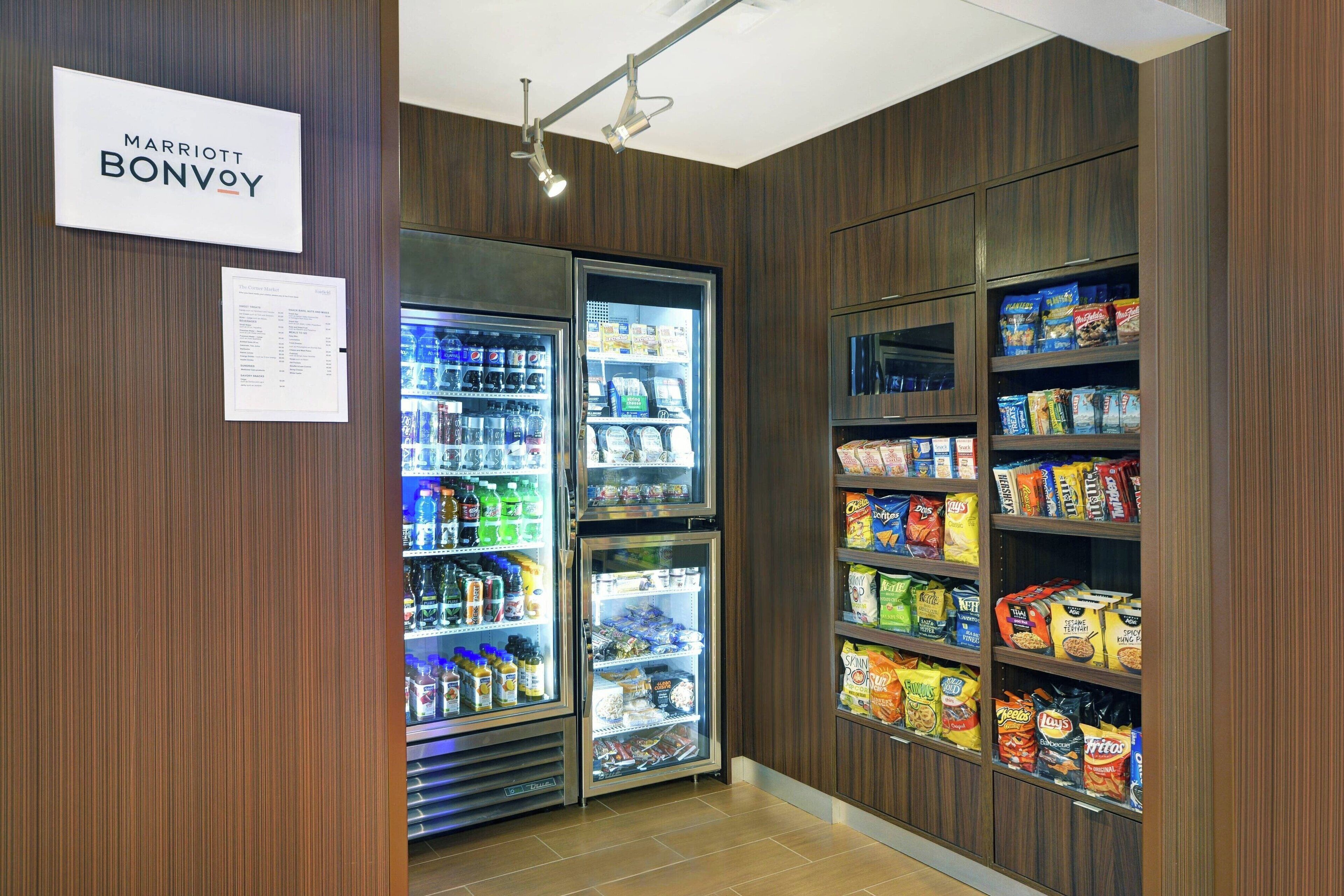 A Marriott Bonvoy self-service area with refrigerated beverage dispensers and snack shelves.