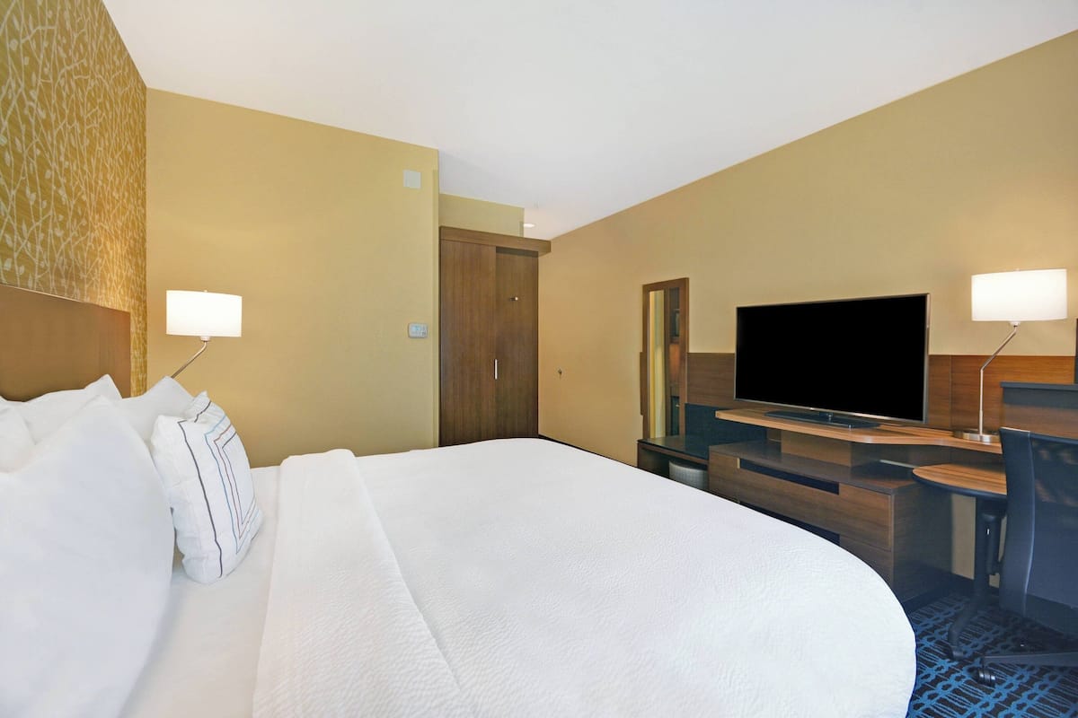 Een hotelkamer met een groot bed, een bureau, een televisie en een spiegel.
