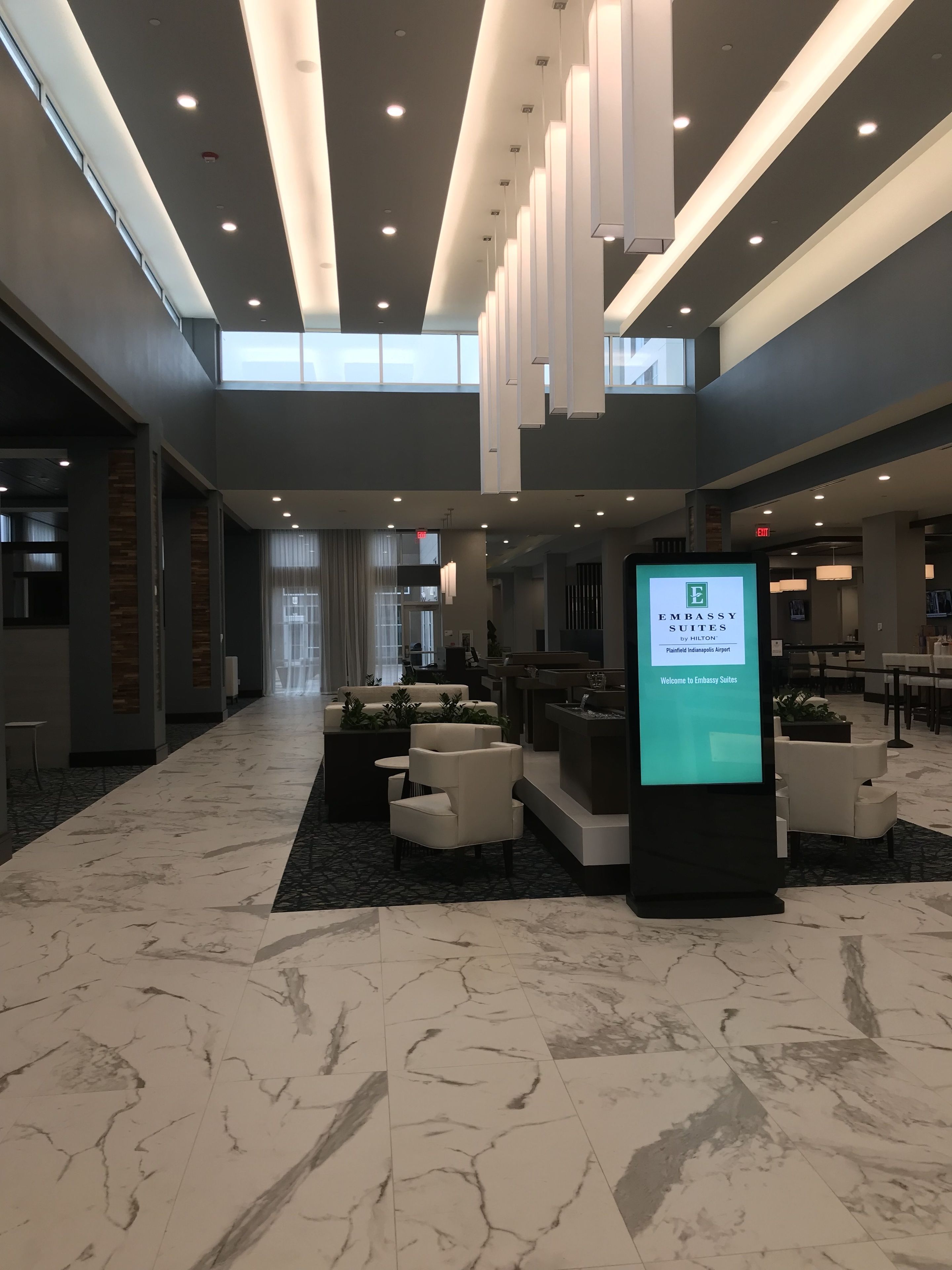 A spacious lobby with a high ceiling, marble flooring, and modern seating areas.
