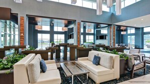 A modern lobby with seating areas, large windows, and a central counter.