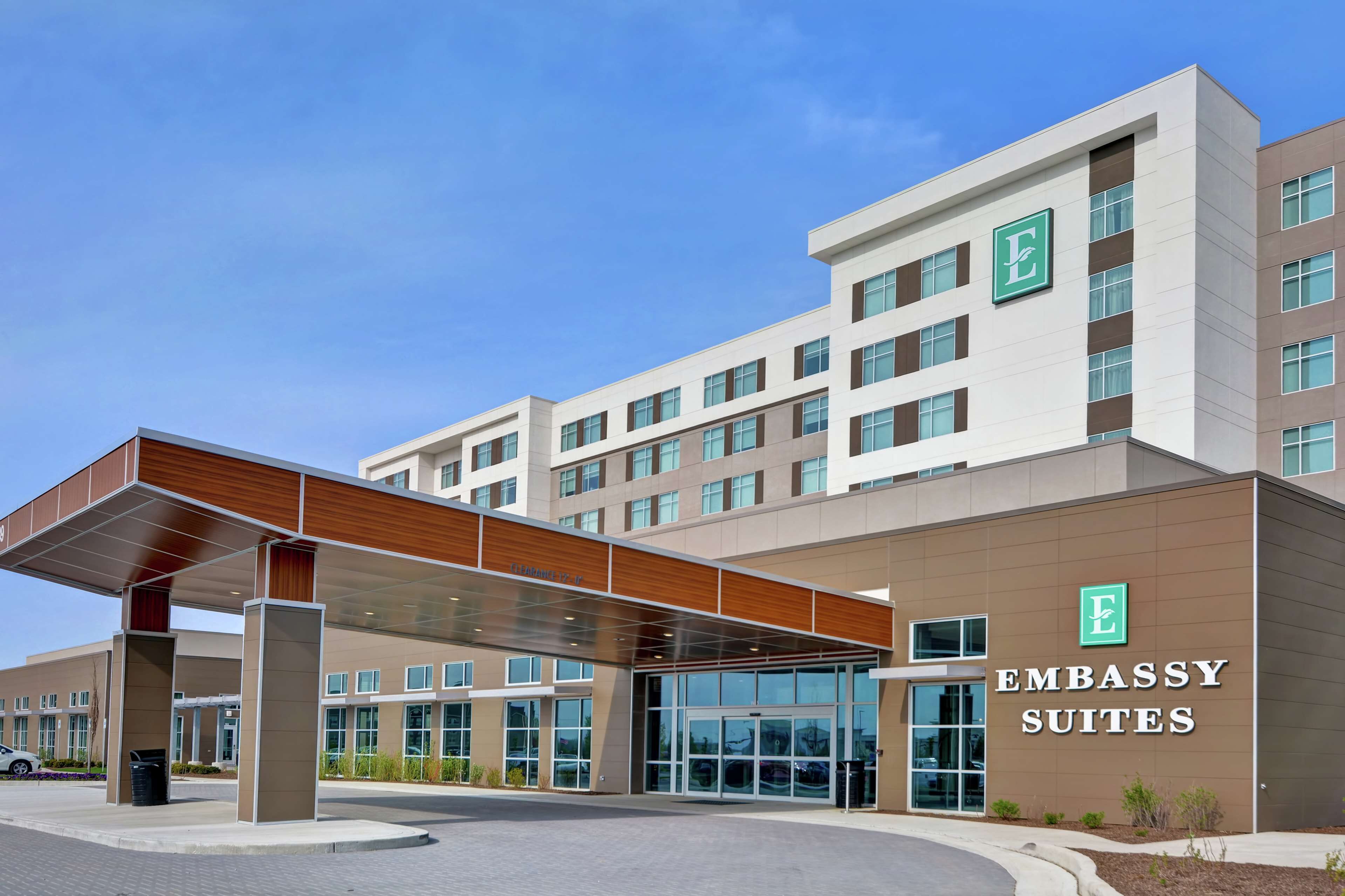 Un edificio moderno con una entrada techada y múltiples ventanas, identificado como "Embassy Suites".