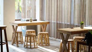 A dining area with a wooden table and four wicker stools.