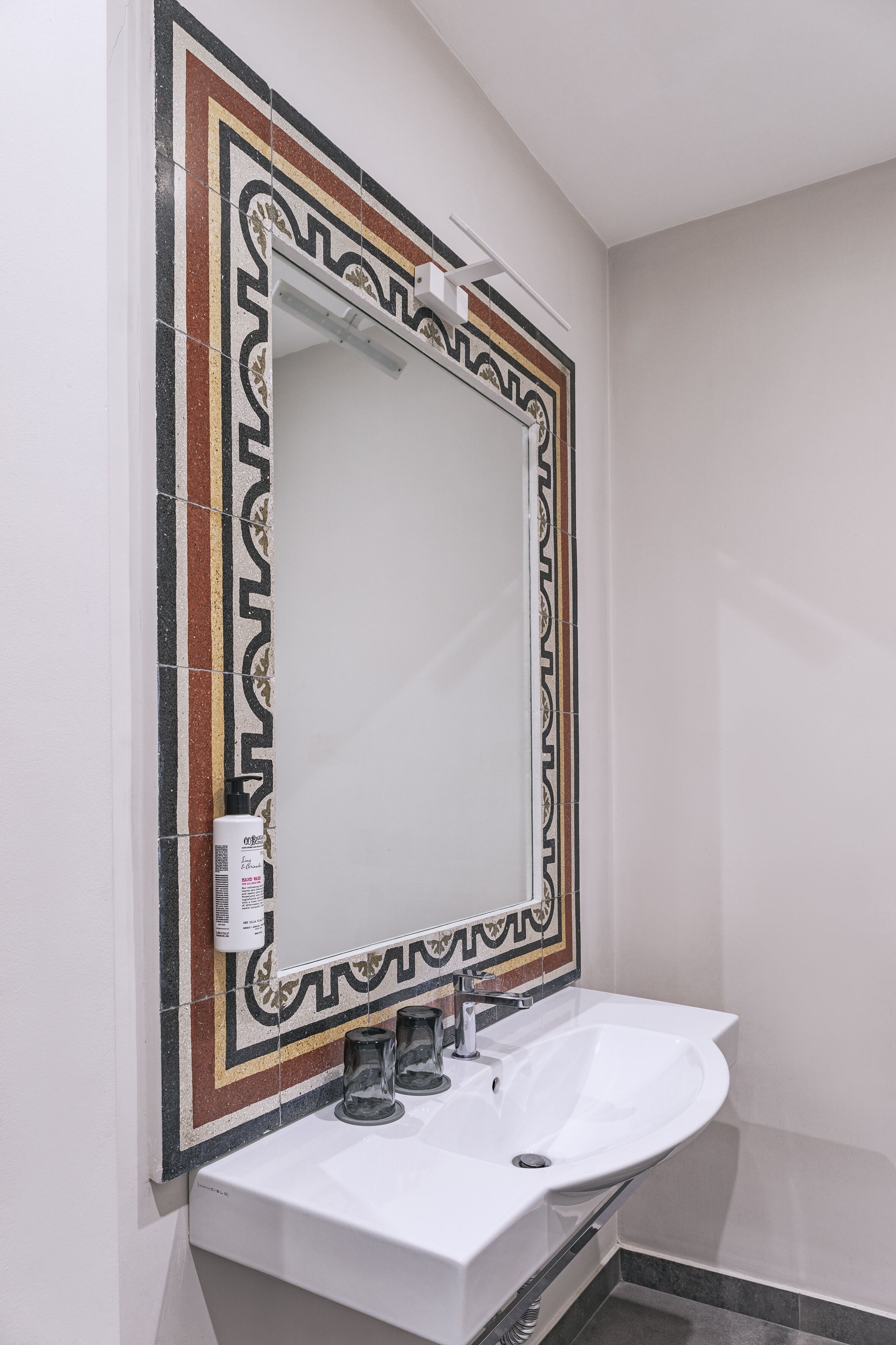 Un bagno con un lavandino bianco, uno specchio con cornice decorativa e un portasciugamani.