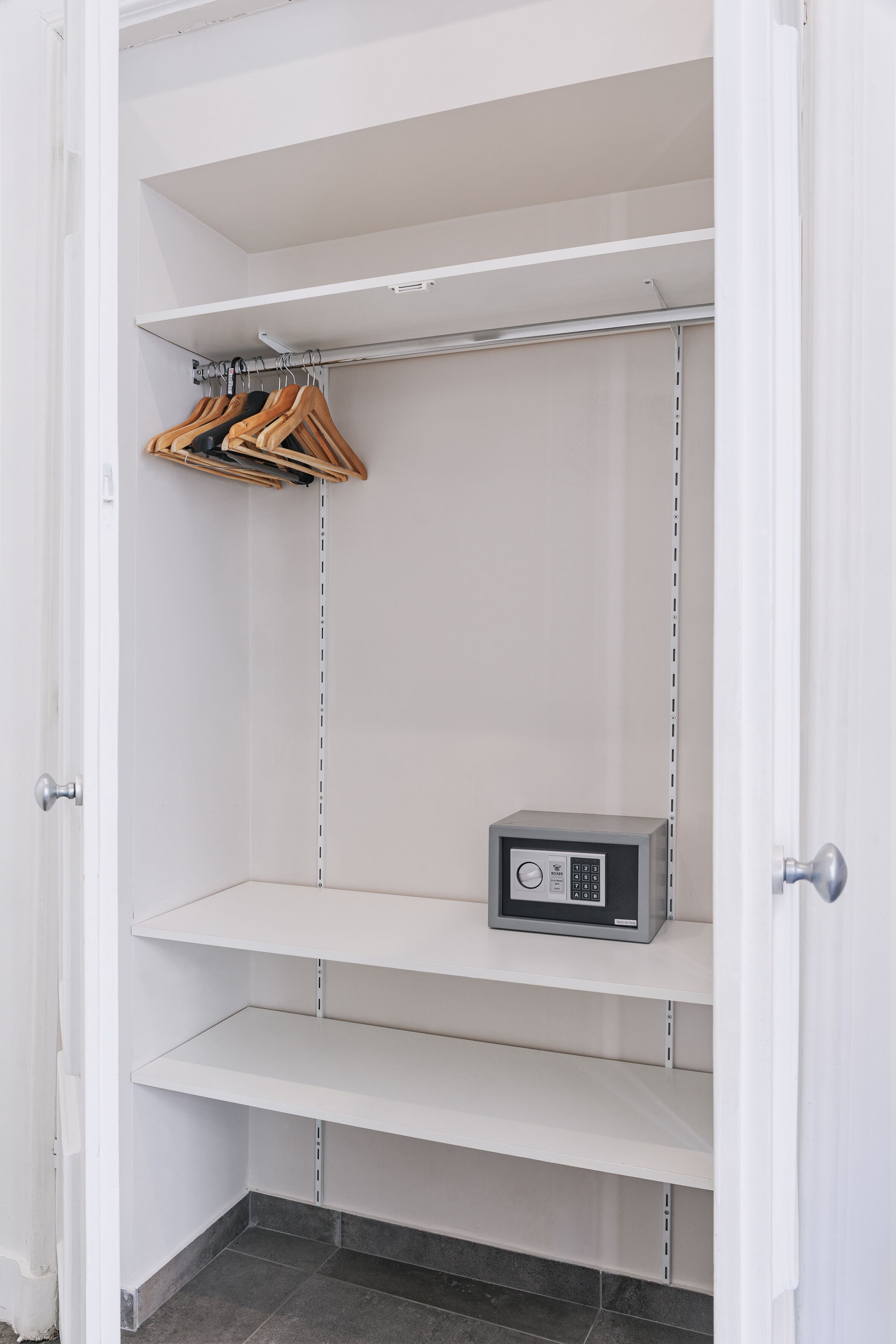 A closet with open doors, containing shelves and a hanging rack.