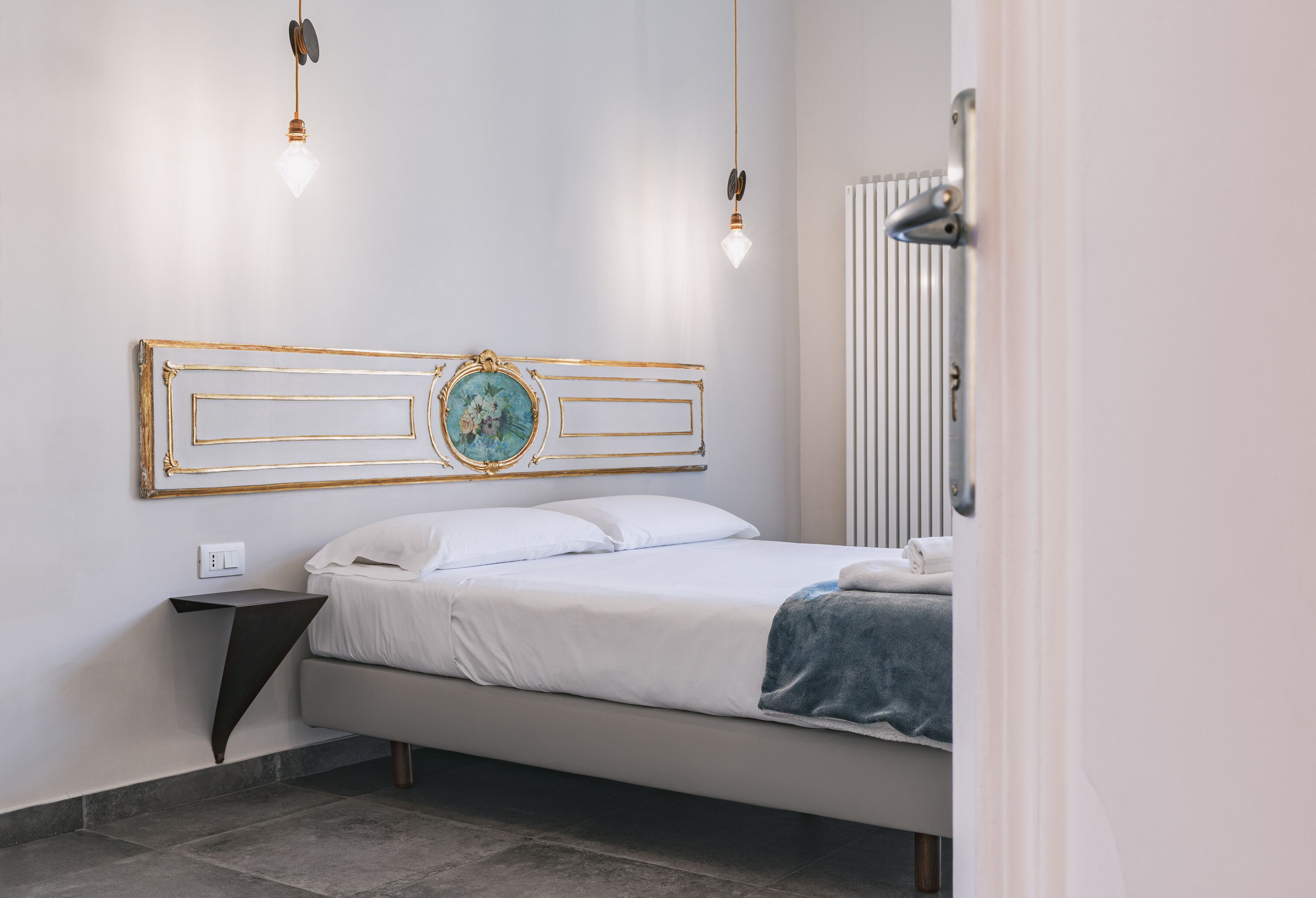A modern bedroom with a bed, a bedside table, and a wall-mounted light fixture.