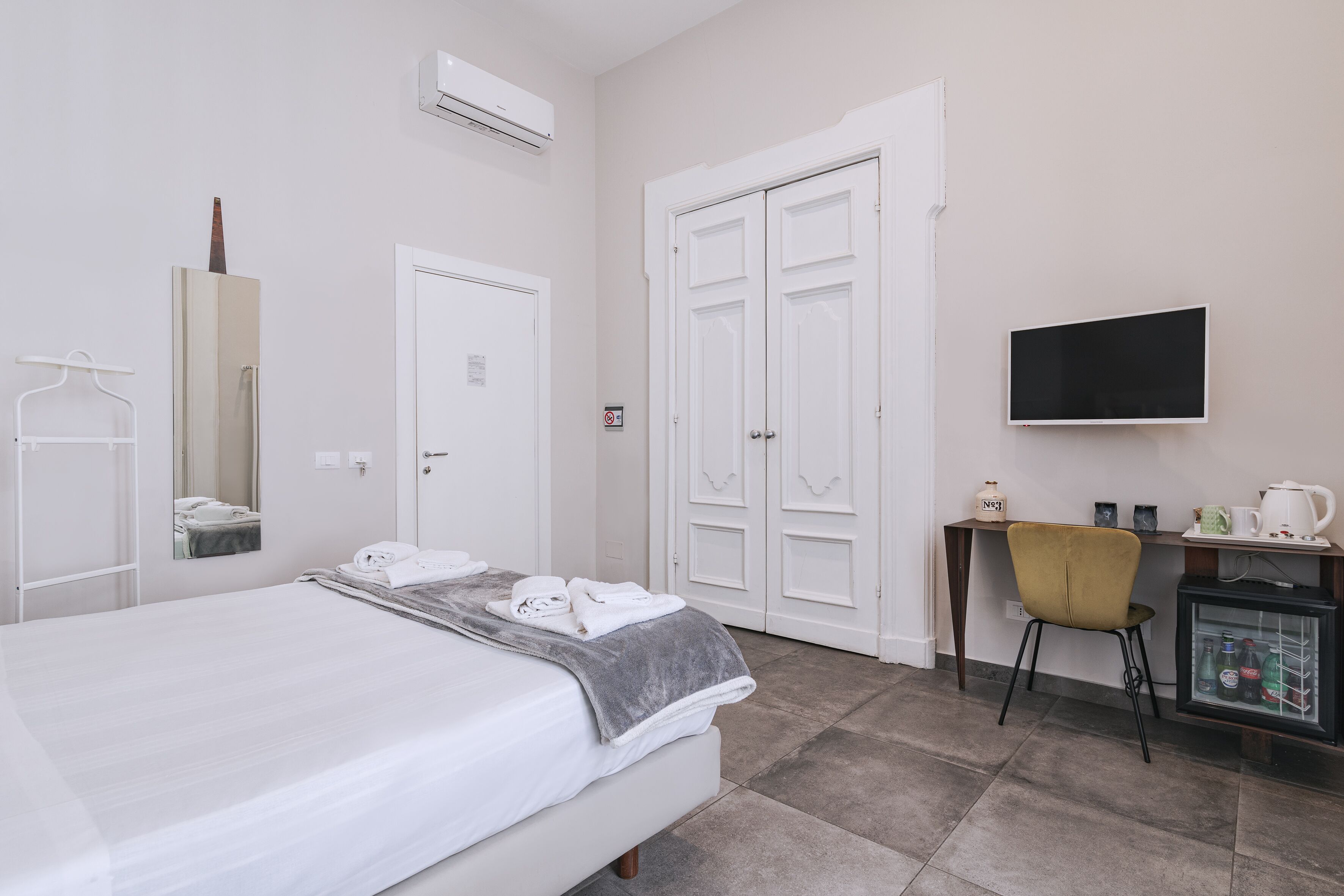 Habitación de hotel con cama, escritorio, silla, televisor y minibar.
