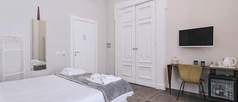 Habitación de hotel con cama, escritorio, silla, televisor y minibar.