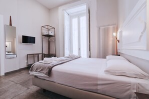 A modern hotel room with a bed, a TV, a wardrobe, and a radiator. - La Smorfia (Naples)