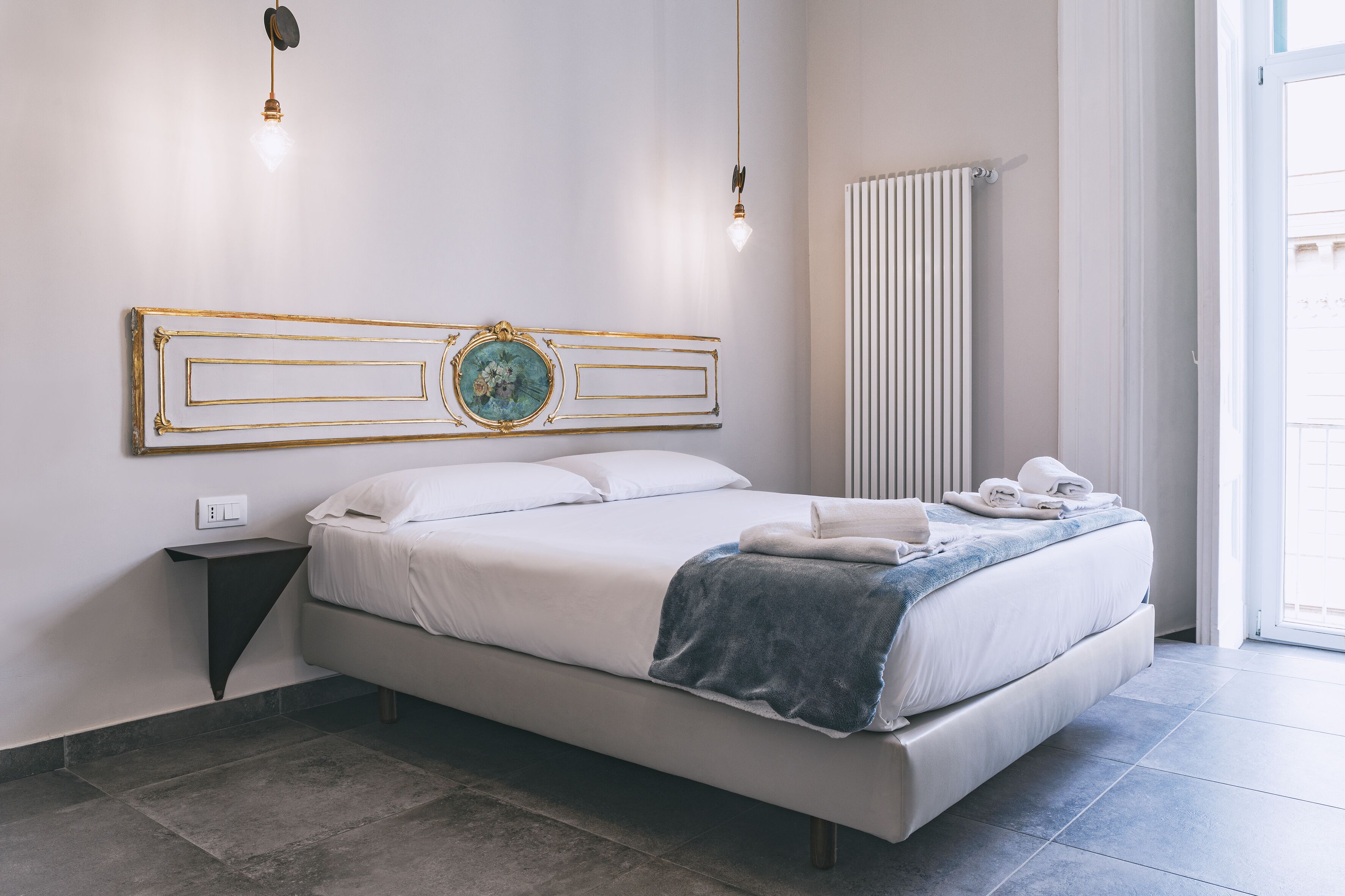 Un dormitorio moderno con una cama grande, un adorno en la pared, una mesita de noche y un radiador.