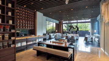 A spacious, modern lounge area with a central seating area, a coffee bar, and a view of the outdoors.