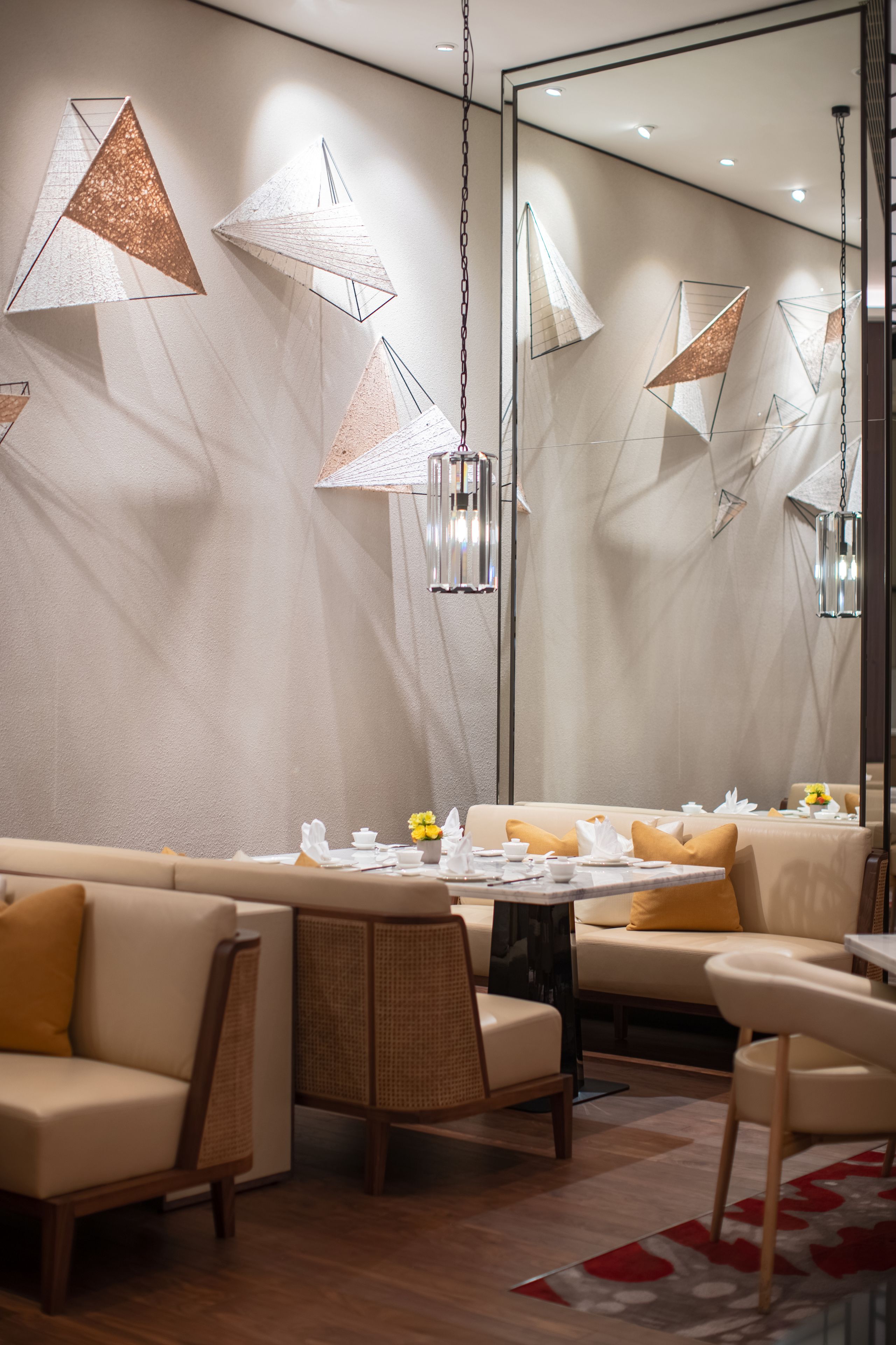 A modern dining area with a sofa, chairs, a table set for dining, and pendant lights.