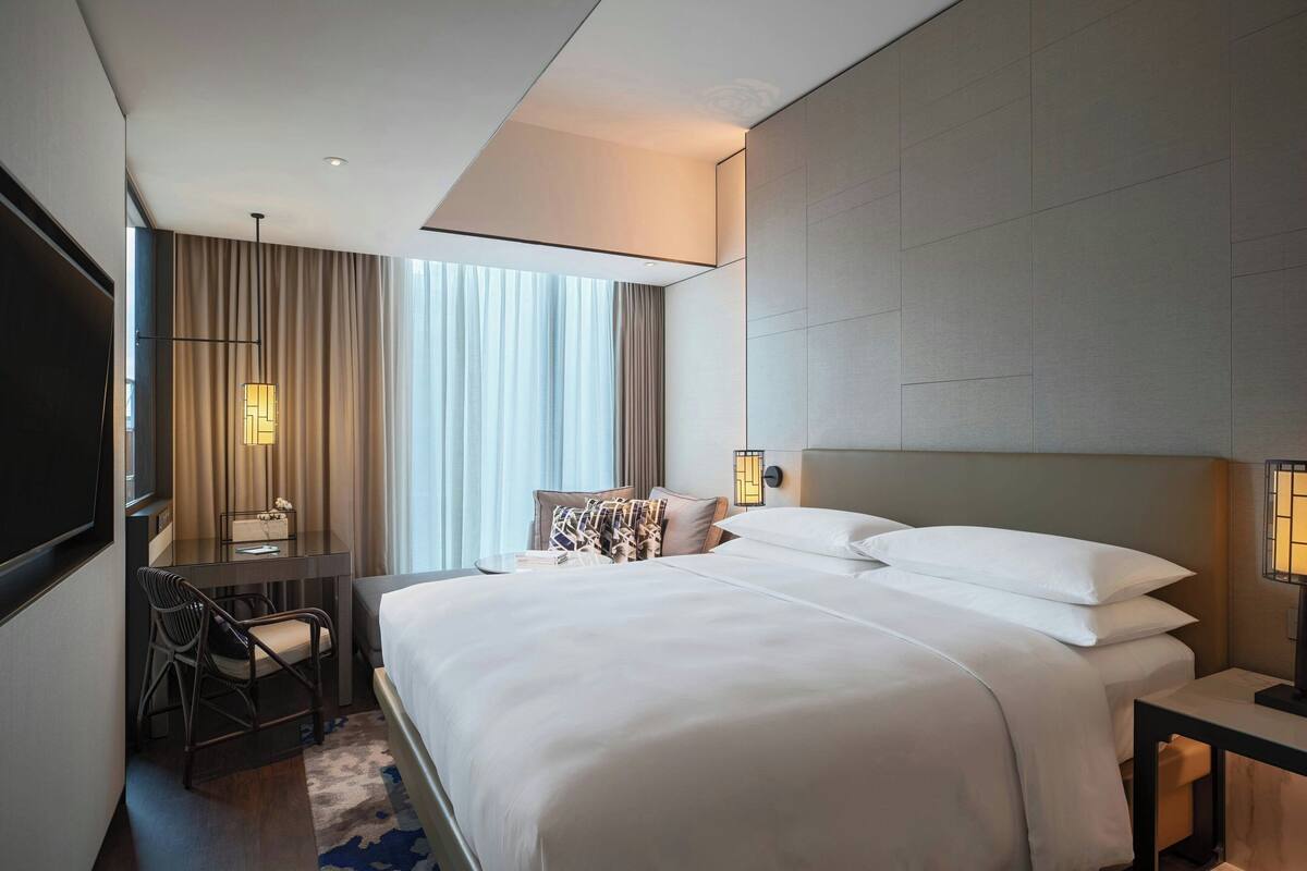 Una habitación de hotel moderna con una cama grande, un escritorio y una silla.