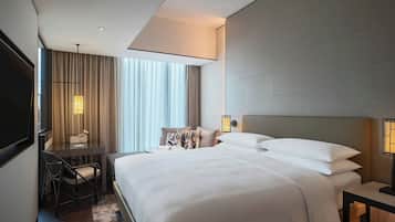 A modern hotel room with a large bed, a desk, and a chair.