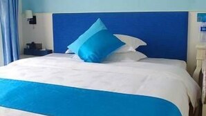 A hotel room with a bed, a nightstand, and a lamp.