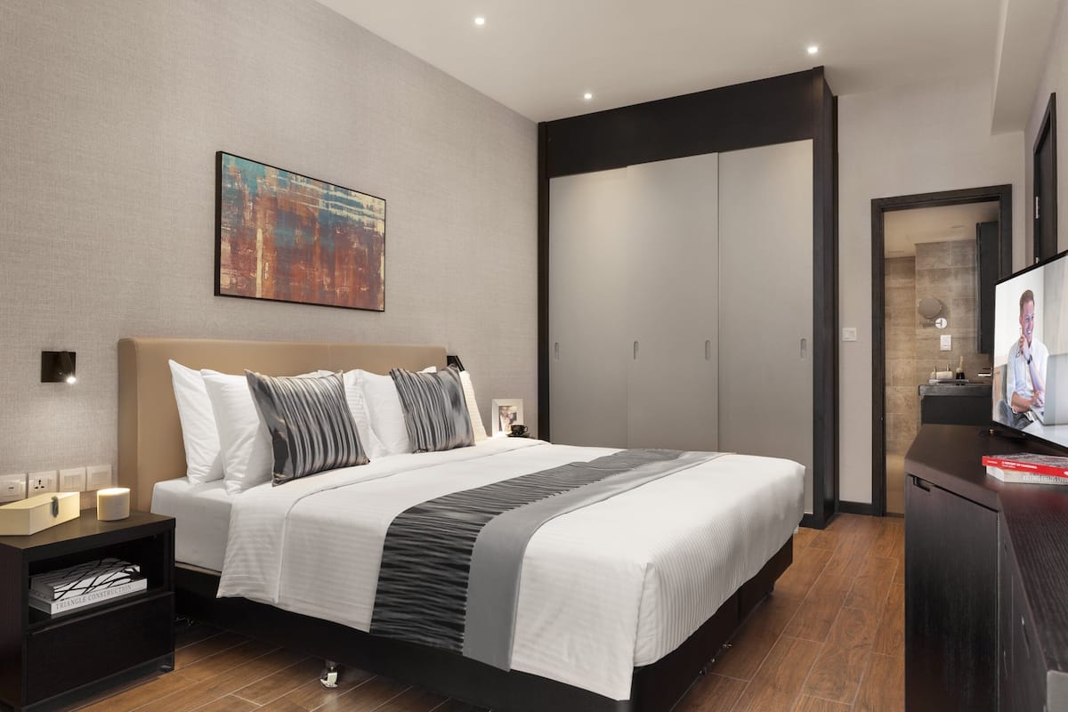 Ein modernes Hotelzimmer mit einem großen Bett, einem Fernseher und einem Kleiderschrank.