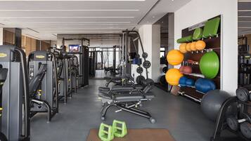 Et fitnesscenter med forskellig træningsudstyr, styrkeløftstationer og træningsbolde.