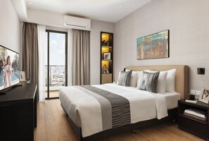 Een moderne hotelkamer met een groot bed, een televisie, een boekenkast en uitzicht over de stad.