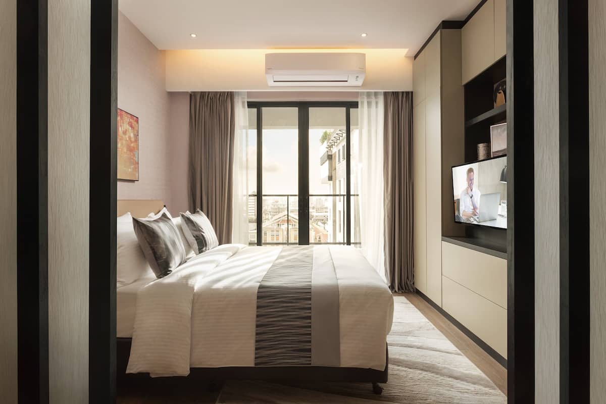 Ein modernes Hotelzimmer mit einem großen Bett, einem Flachbildfernseher und Blick auf die Stadt durch das Fenster.