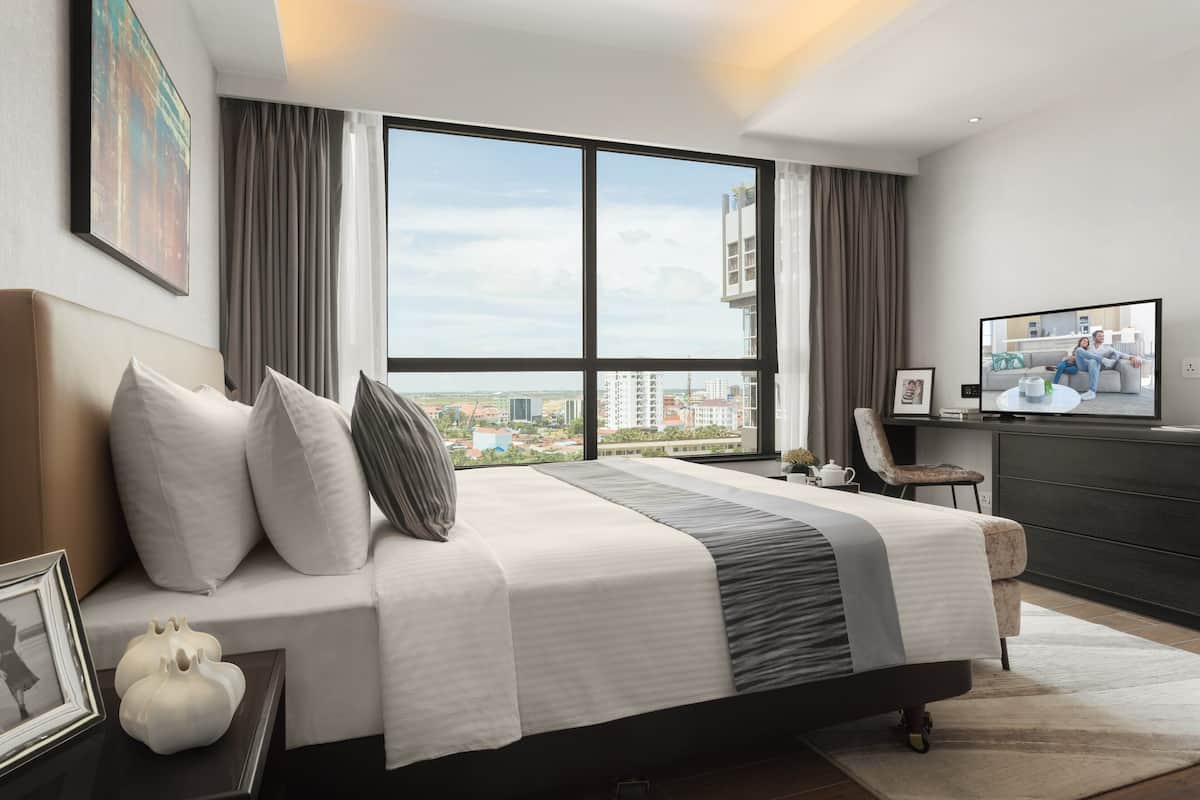 Ein modernes Schlafzimmer mit einem großen Bett, einem Fernseher und Blick auf die Stadt.