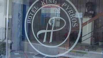 Un letrero de hotel con el nombre "HOTEL KING PYRROS" y un símbolo que parece una corona.