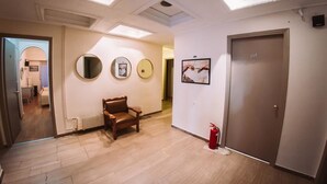 Un pasillo con una silla de cuero marrón, un extintor y una puerta con el número 105.
