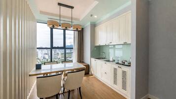Una cocina moderna con un ventanal grande, un comedor con mesa y sillas, y armarios blancos.