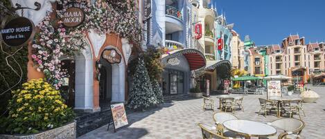 A charming street with a coffee shop named Mama Moon and a building with a unique architectural design.