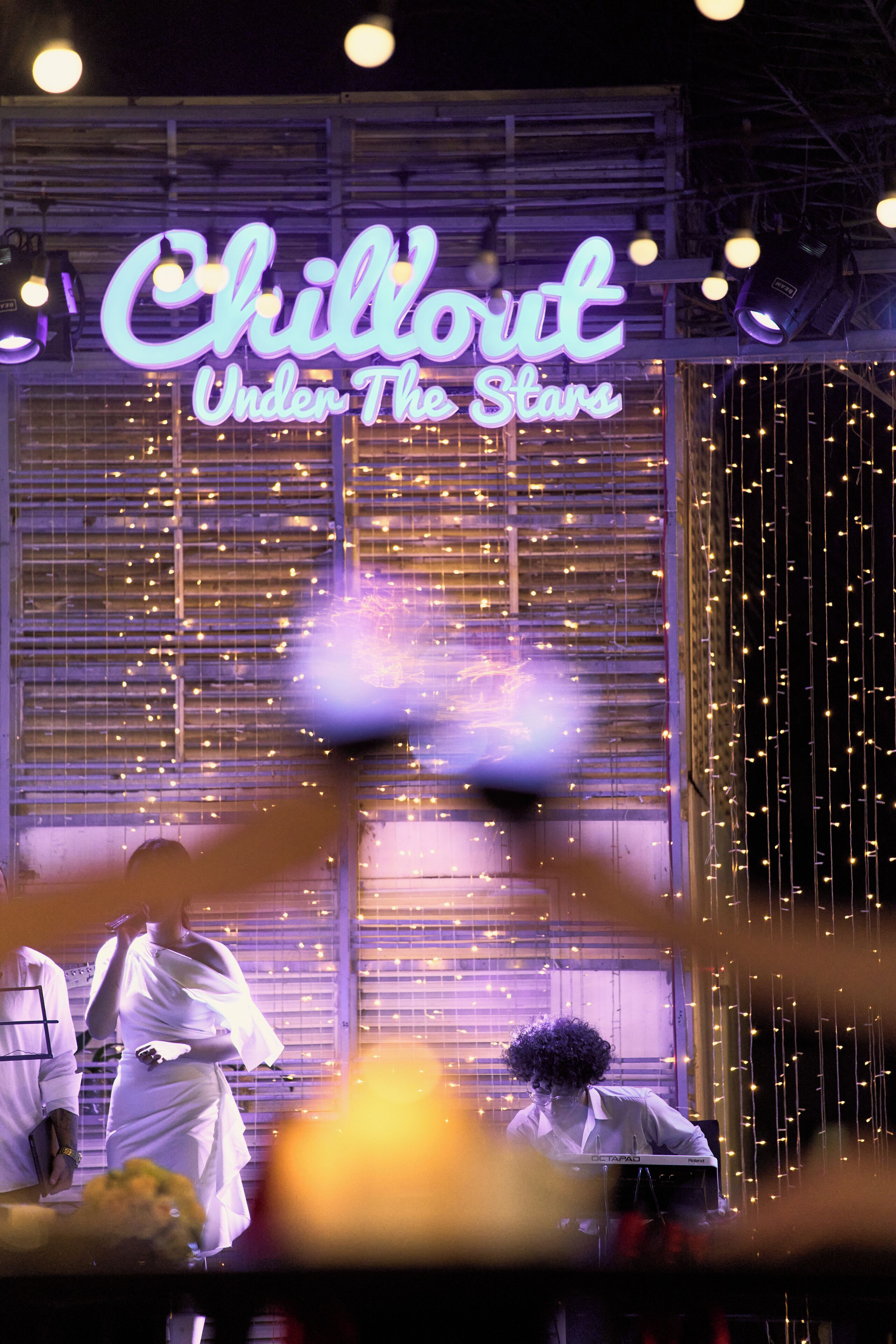 Ein Neon-Schild mit der Aufschrift 'Chillout Under The Stars' und eine Fensterdekoration mit Lichtern.