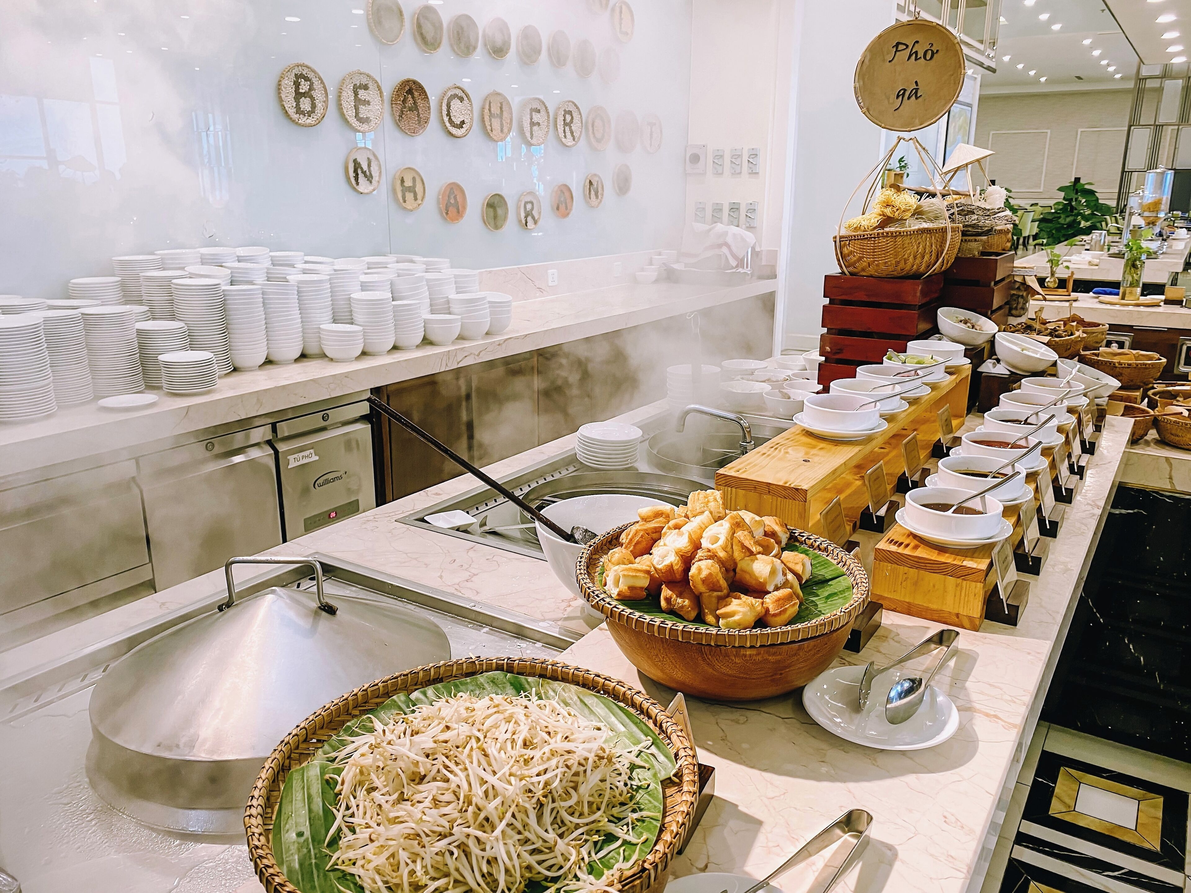 A buffet setup with various dishes and a wall displaying the word "BEACHFRONT".