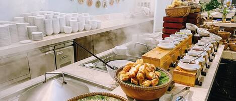 A buffet setup with various dishes and a wall displaying the word "BEACHFRONT".