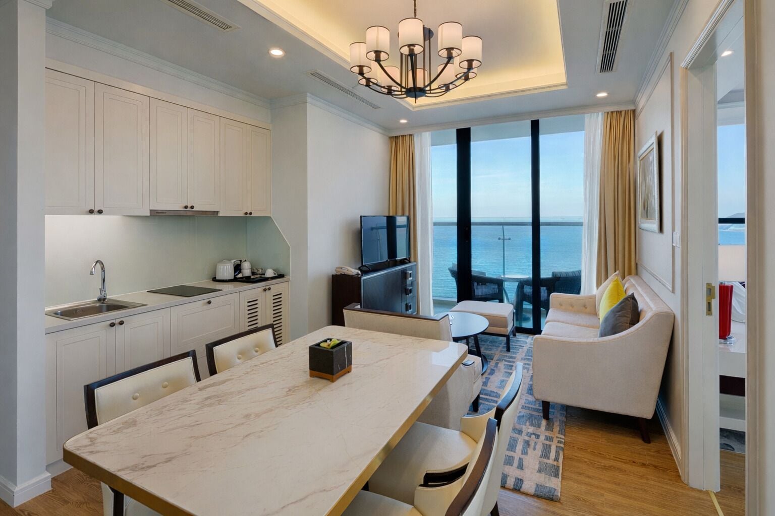 Una habitación de hotel moderna con cocina, comedor y un balcón con vistas al mar.