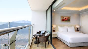 Une chambre d’hôtel avec un balcon, un lit, une table de chevet, une chaise et un tableau.