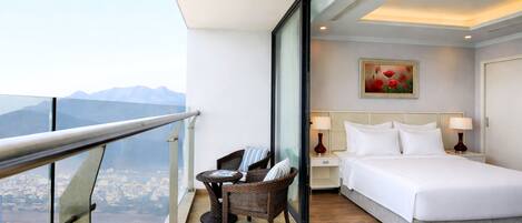 Une chambre d’hôtel avec un balcon, un lit, une table de chevet, une chaise et un tableau.