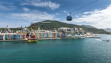 A waterfront cityscape with colorful buildings, a cable car, and a mountain in the background.