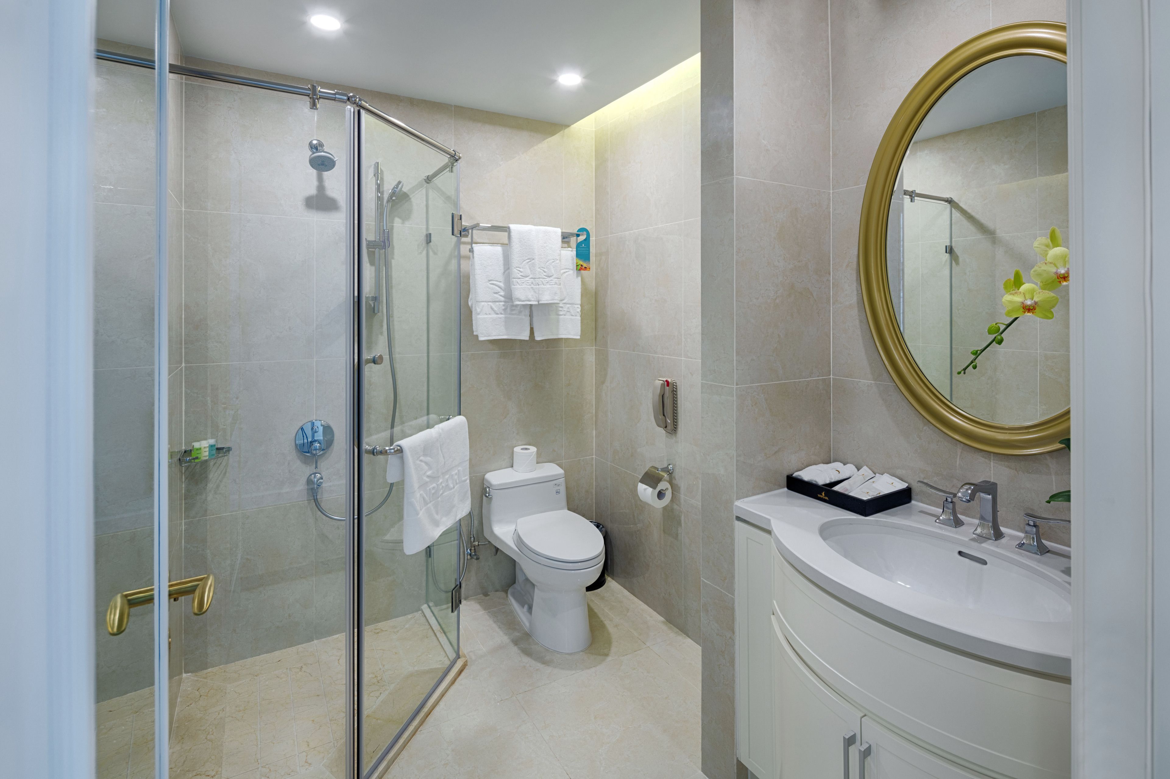Ein modernes Badezimmer mit Glasdusche, Toilette und Waschbecken inklusive Spiegel.