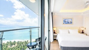Une chambre d’hôtel avec un balcon, un lit, une table de chevet, une lampe et un tableau.