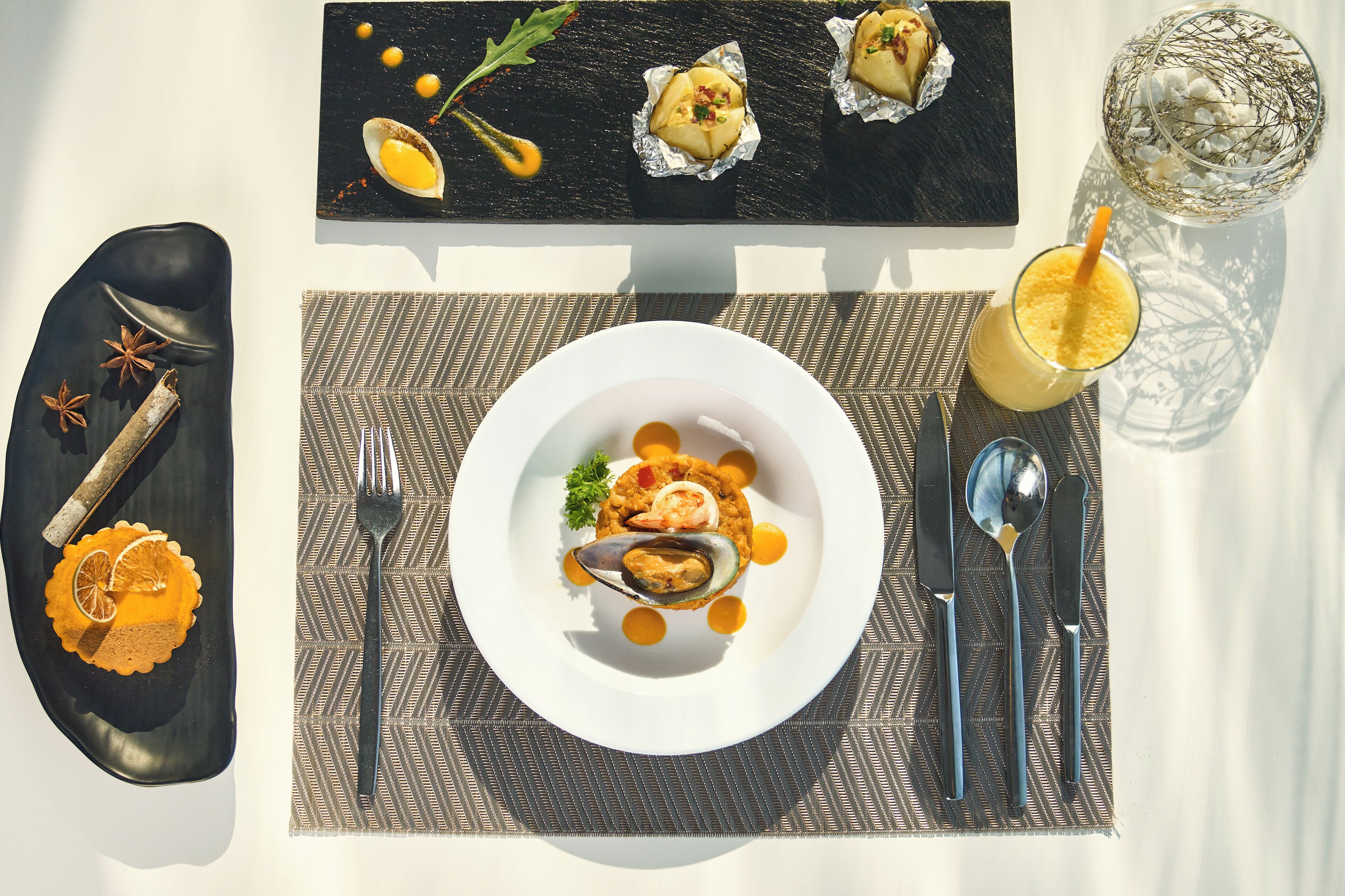Una mesa de comedor con un plato de mariscos, un vaso de bebida y un cuenco decorativo.