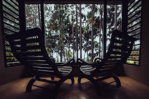 Two rocking chairs facing a window with a view of tall trees. - L'Exil Lodges (Riviere des Anguilles)