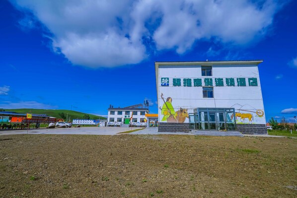 A building with a mural of a horse and rider, a sign with Chinese characters, and a clear blue sky.
