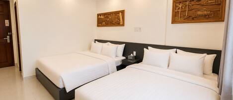 A hotel room with two beds, a dark headboard, a wall-mounted artwork, and a ceiling light fixture.