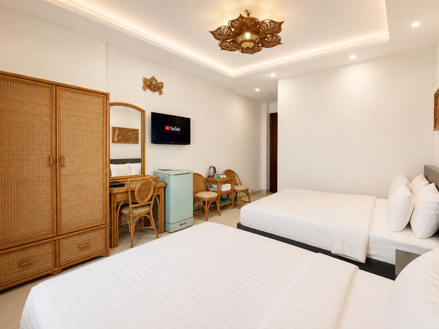 A hotel room with two beds, a desk, a chair, a television, and a wardrobe.