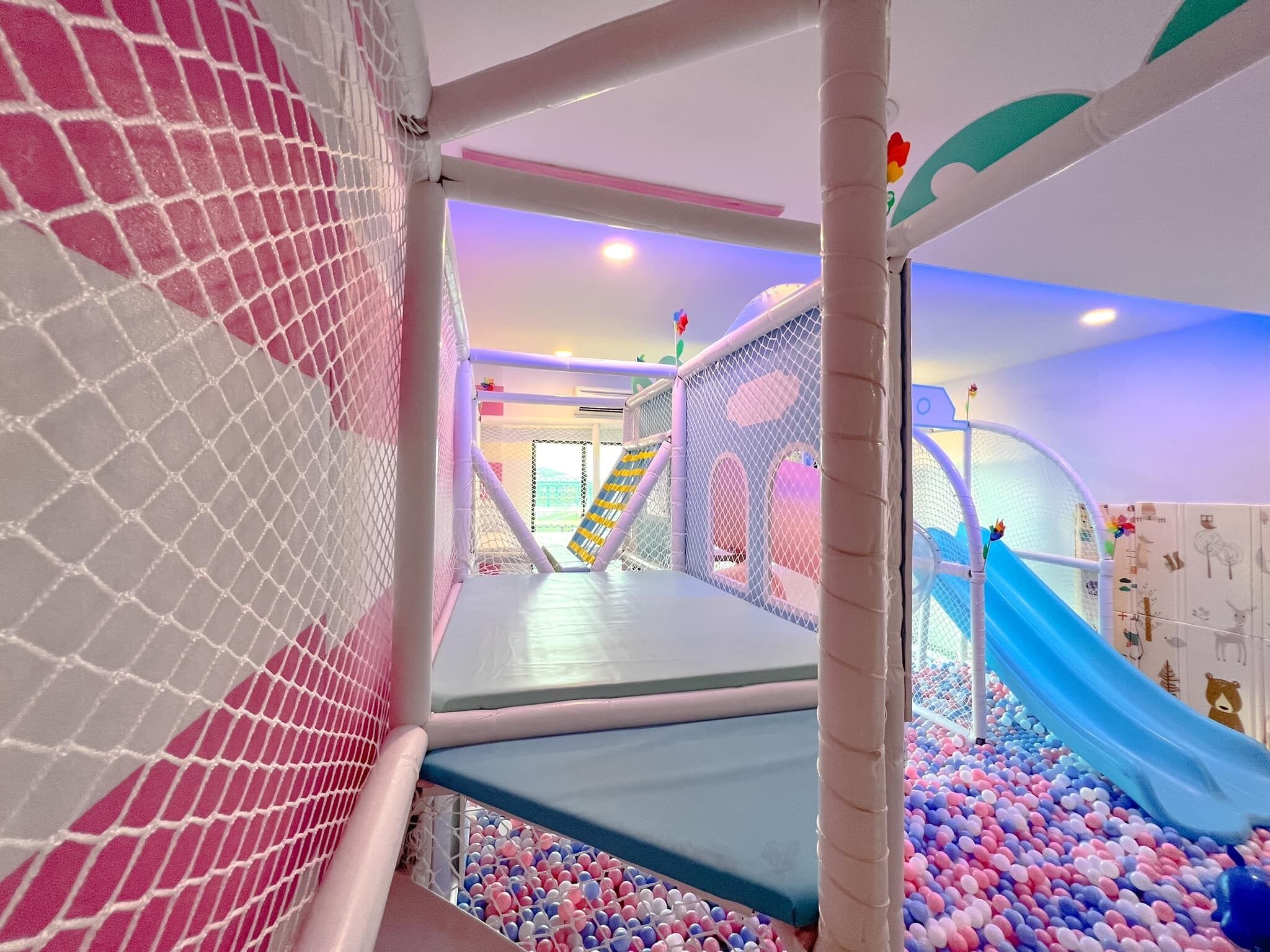 An indoor play area with a slide, ball pit, and netted climbing structure.