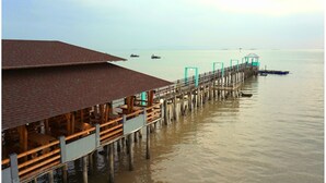 A wooden pier extending into calm water with a covered seating area on one end. - Kukup Xiang Holiday Home (Kukup)