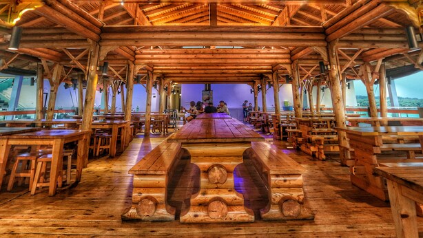 A wooden interior with tables and benches arranged in rows, a central stage, and a view of the outdoors. - Kukup Xiang Holiday Home (Kukup)
